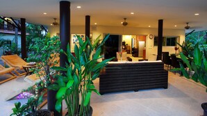 Un espacio interior amplio con mostrador de recepción, sillones de descanso y plantas en macetas.