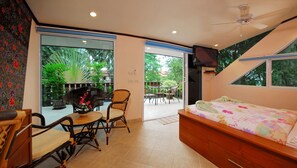 A bedroom with a bed, a chair, a table, and a TV.