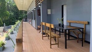 An outdoor covered patio area with wooden benches and tables, potted plants, and a view of the surrounding greenery. - Tatay Seseng's Apartment  Panglao (Panglao)