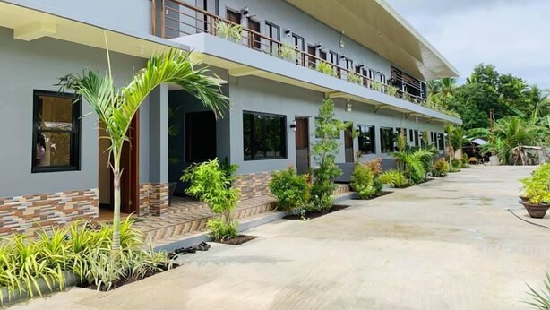 A two-story building with a covered walkway, multiple windows, and a variety of plants. - Tatay Seseng's Apartment  Panglao (Panglao)