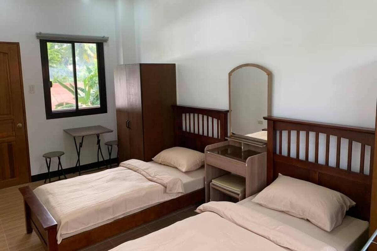 Une chambre avec deux lits, un bureau, une armoire et une fenêtre.