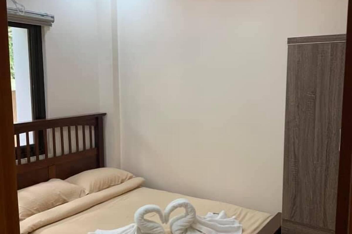 Une chambre à coucher avec un lit en bois, une literie de couleur beige et une armoire.