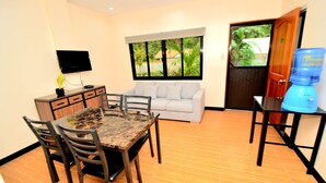 A dining area with a table, chairs, a sofa, a television, and a water dispenser. - Tatay Seseng's Apartment  Panglao (Panglao)