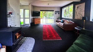 A living room with a fireplace, a sofa, a TV, and a large window.