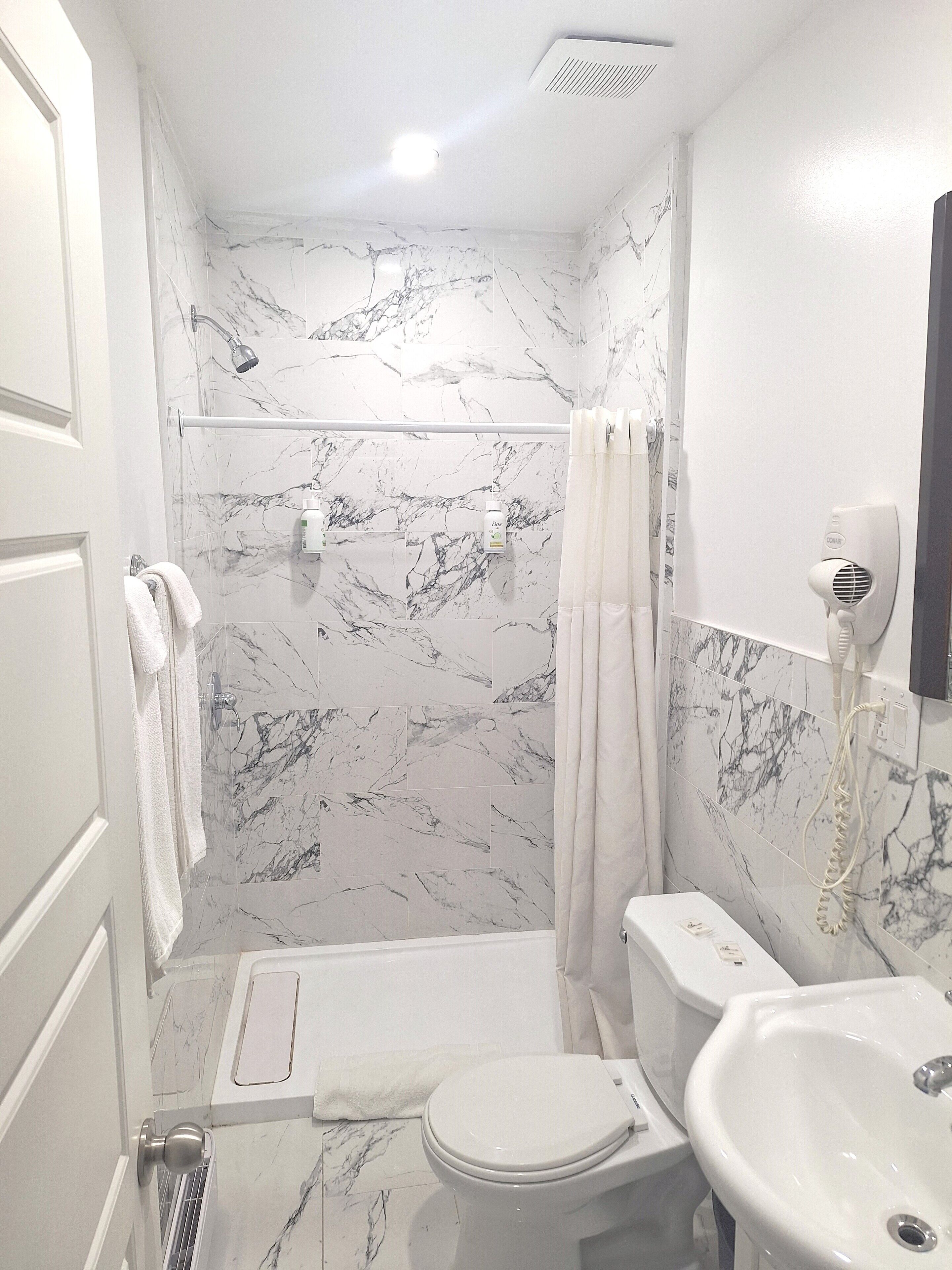 A bathroom with a toilet, sink, and shower area.