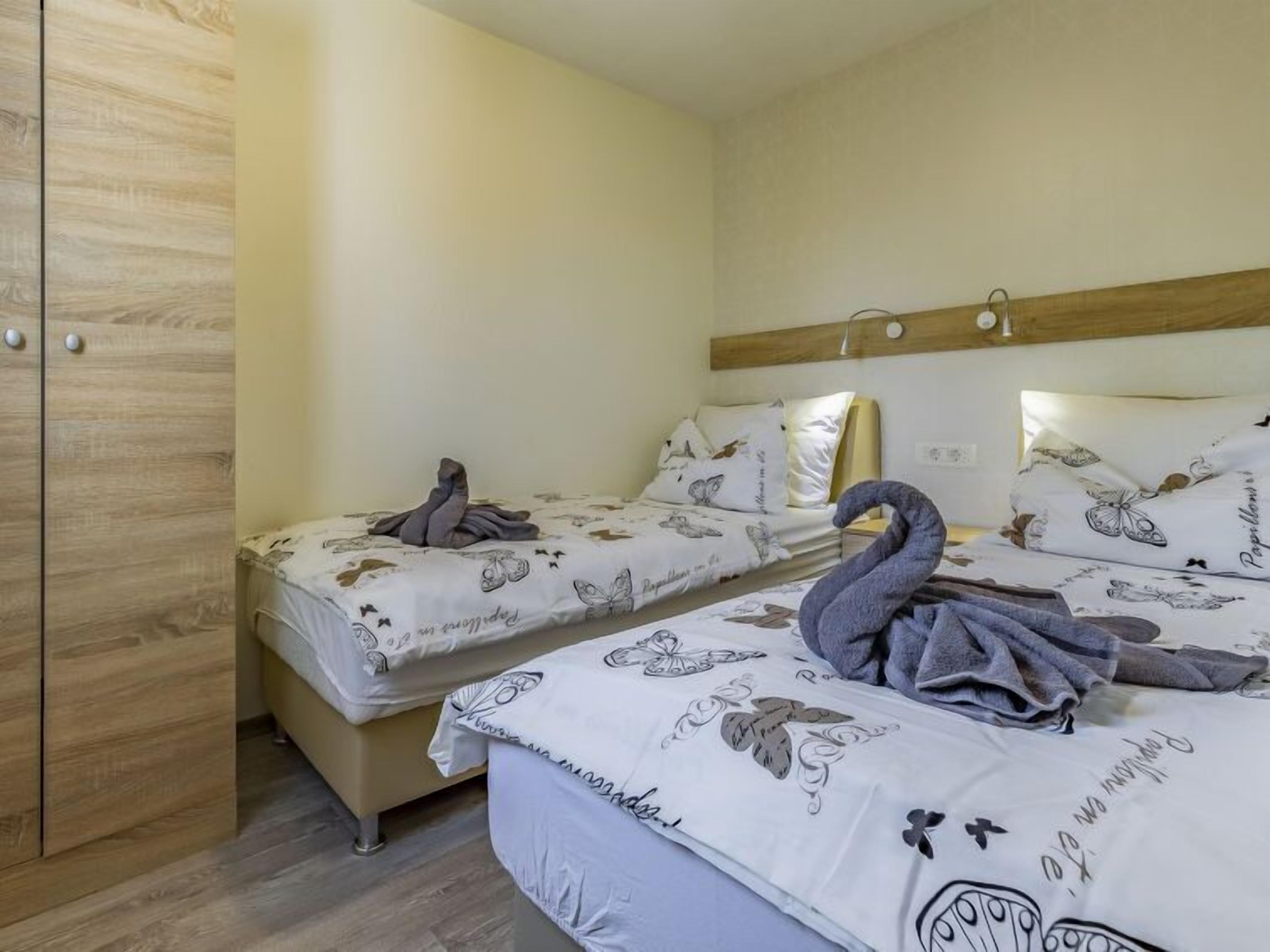 Un dormitorio con dos camas, cada una con una toalla con forma de cisne, y un armario de madera.