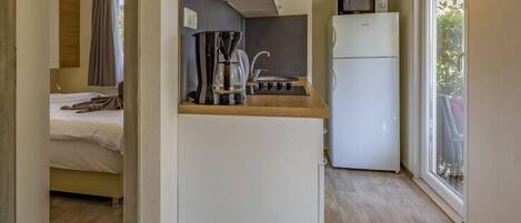 Uma cozinha compacta equipada com cafeteira, micro-ondas e frigorífico.