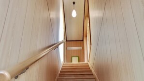 Una escalera de madera con barandilla que conduce a una habitación con una pared de acento verde y una lámpara colgante.