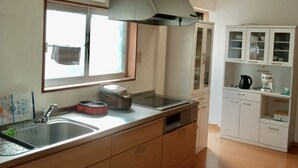 Una cocina con una isla grande, una ventana, horno empotrado y armarios blancos.