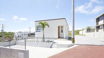 A modern building with a white exterior, a small entrance, and a palm tree in the foreground.