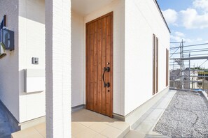 A wooden door with a handle, a white exterior wall, and a small step leading to the entrance. - E-horizon Resort Condominium Nago A (Nago)
