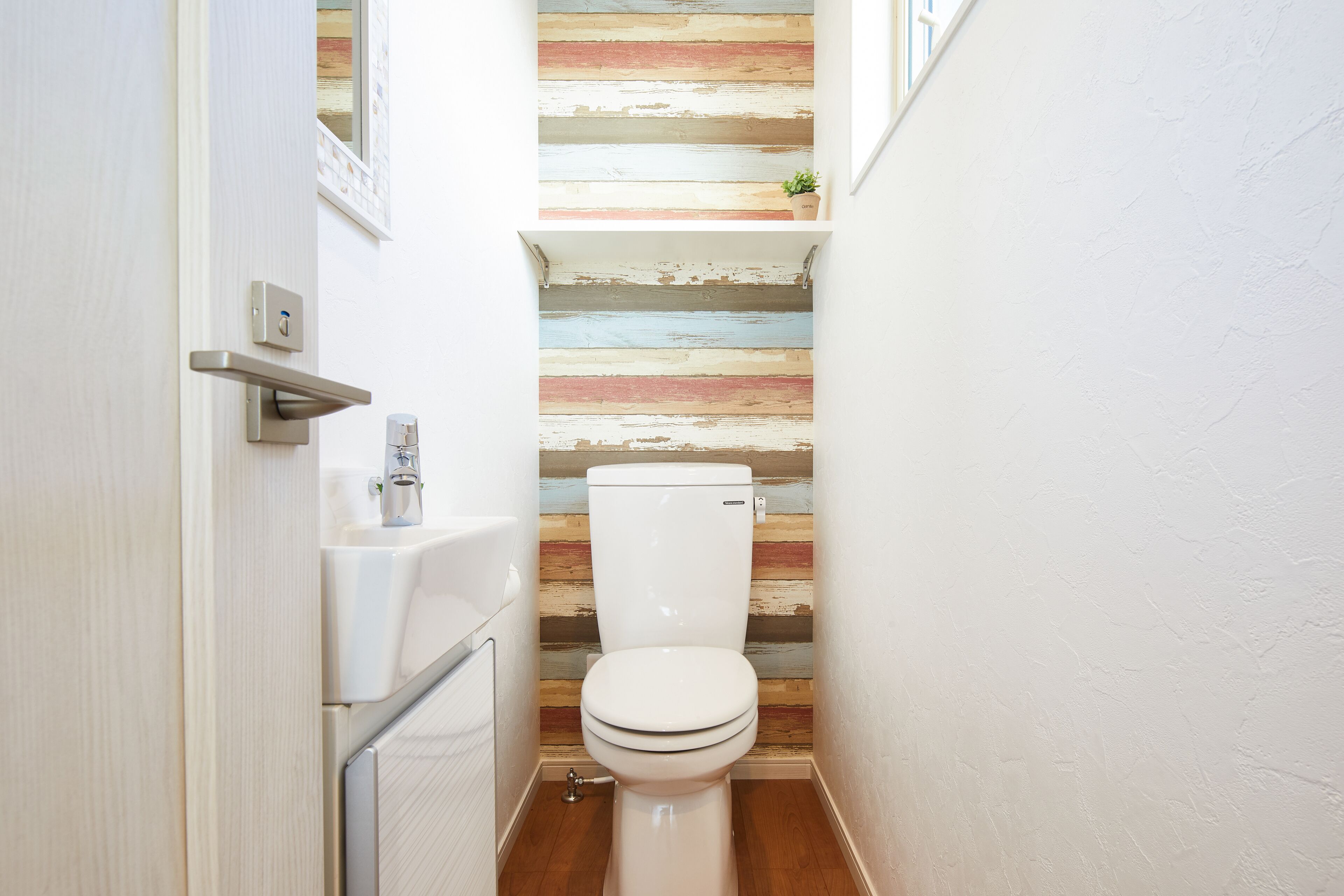 A small bathroom with a wooden wall, a white toilet, and a sink.