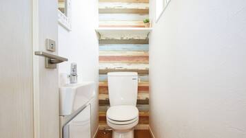 A small bathroom with a wooden wall, a white toilet, and a sink.