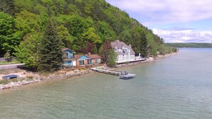 Una proprietà sul lago con un molo, una casa con un balcone e un pendio boscoso.