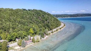 Una zona costiera con vista chiara su una spiaggia, una strada che serpeggia lungo la costa e colline ricoperte da una fitta vegetazione sullo sfondo.