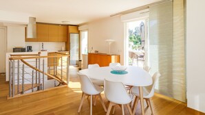 Una cocina moderna con armarios de madera, un refrigerador de acero inoxidable y una zona de bar con taburetes.