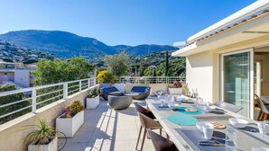 Una terraza en la azotea con zona de comedor, mobiliario exterior y vistas panorámicas a la montaña.