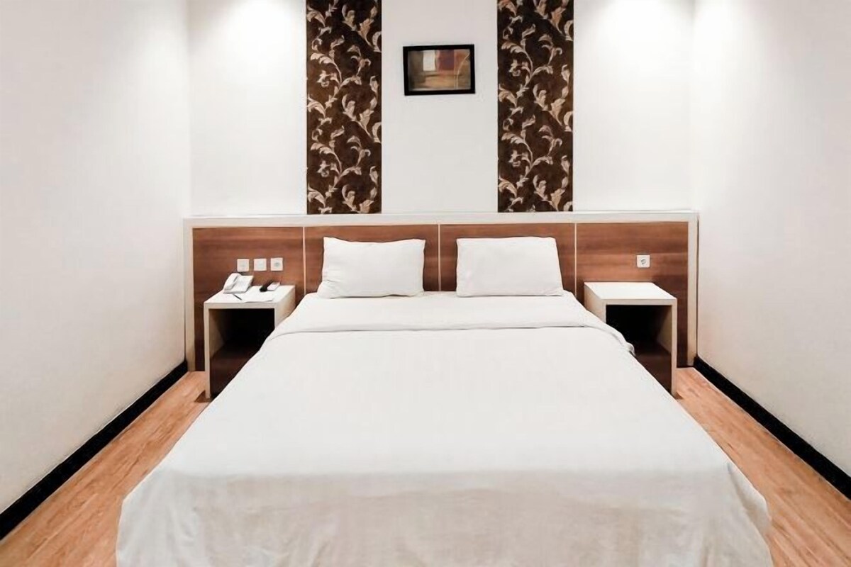 Habitación de hotel con una cama grande, dos mesitas de noche y un cuadro colgado en la pared.