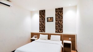 Une chambre d’hôtel avec un grand lit, deux tables de chevet, une petite table et un téléphone fixé au mur.