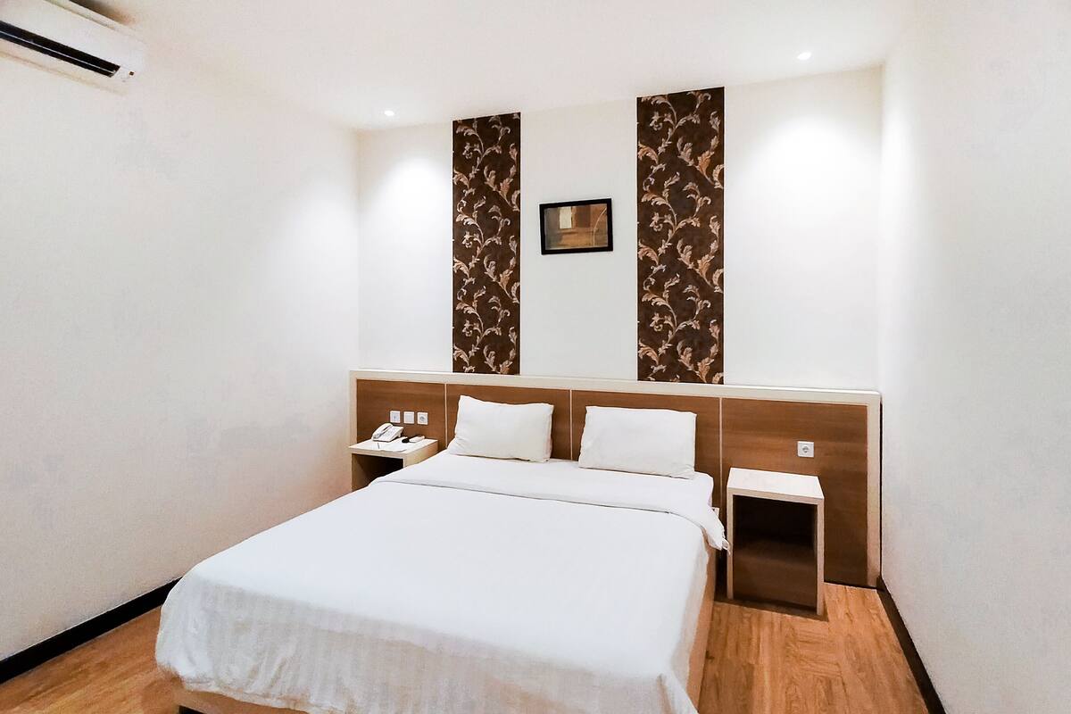Een hotelkamer met een groot bed, twee nachtkastjes en een telefoon aan de muur.