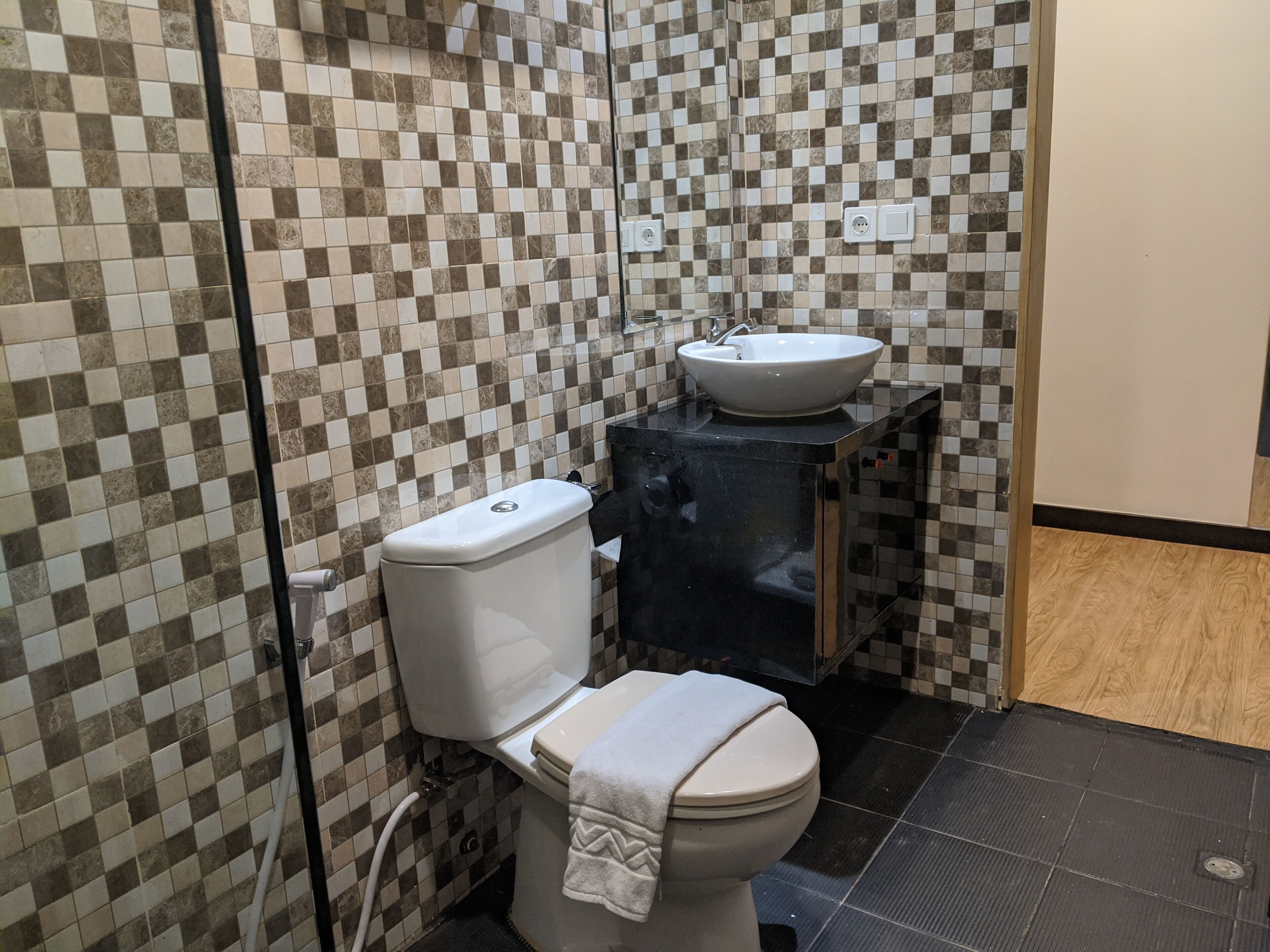 Een badkamer met toilet, wastafel en betegelde wanden.