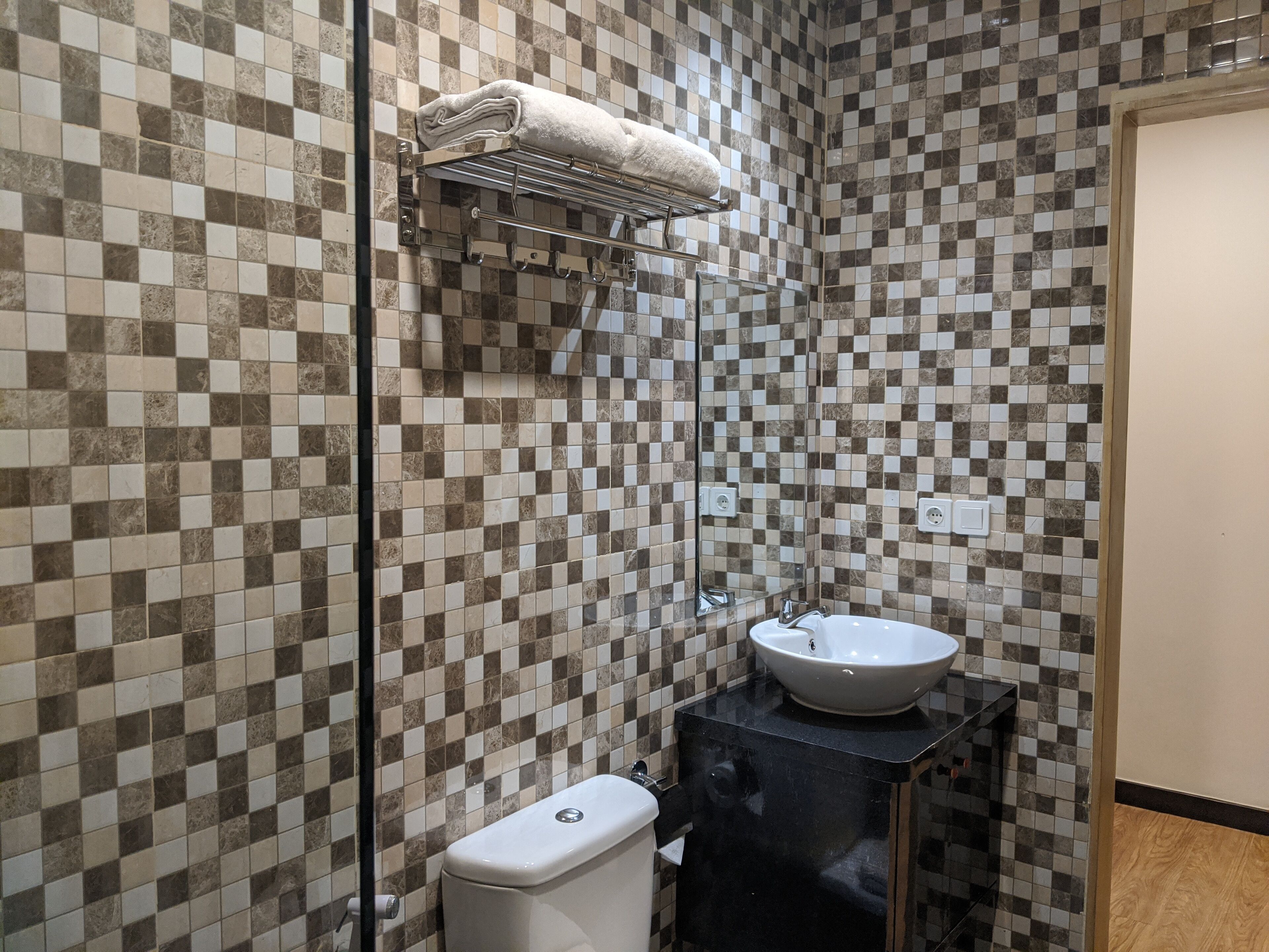 Une salle de bain avec un mur recouvert de carreaux à motifs géométriques, un lavabo blanc et des toilettes.