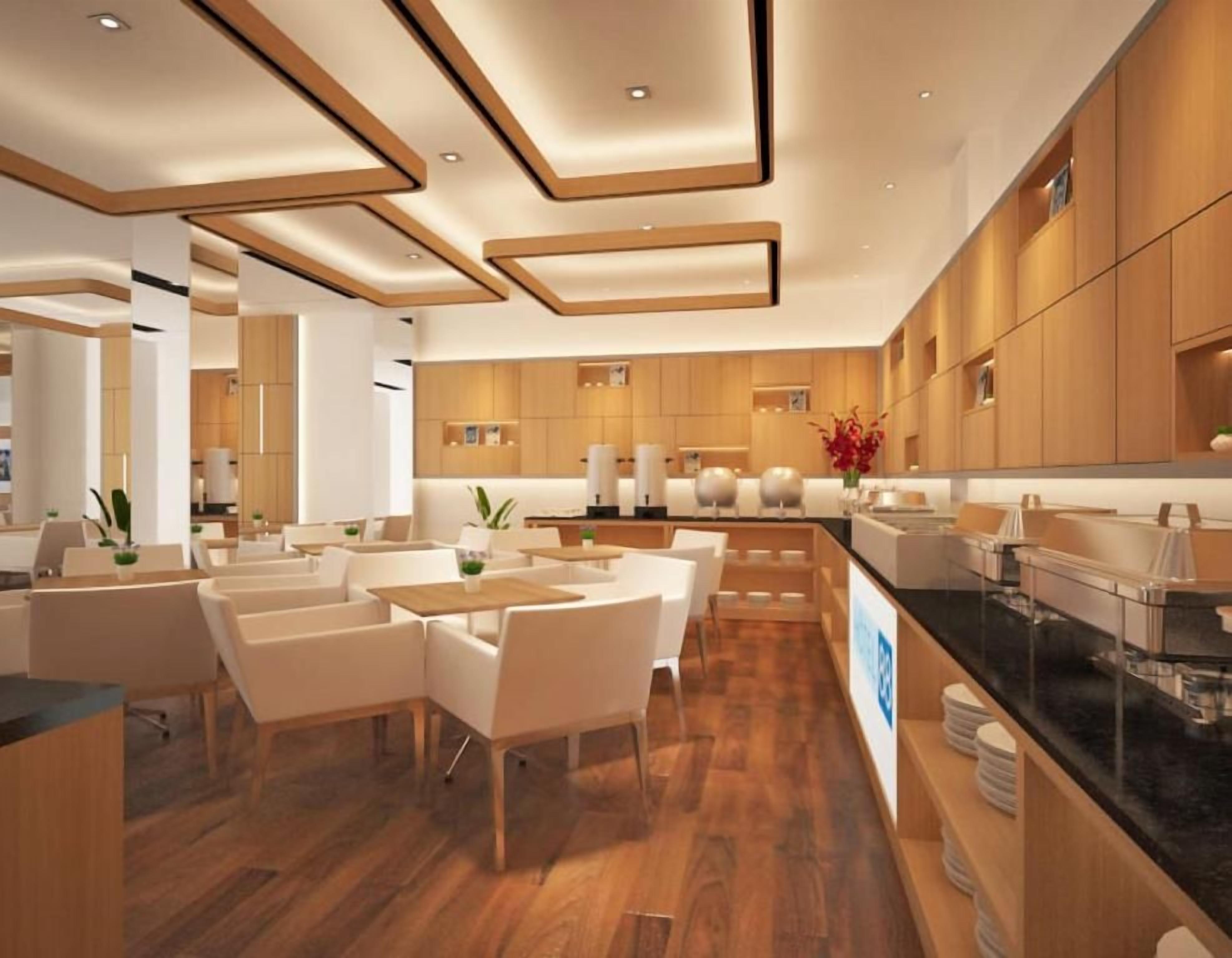 Un hall d’hôtel moderne avec un plancher en bois, des meubles blancs et un comptoir central.