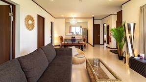 A modern living room with a sofa, a dining area, and a kitchen in the background. - LiB PLUS Villa NAGO (Nago)