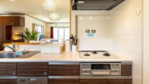 A modern kitchen with a built-in dishwasher, a stove, and a large island with a sink. - LiB PLUS Villa NAGO (Nago)