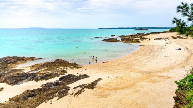A beach with clear turquoise water, rocky areas, and a sandy shore. - LiB PLUS Villa NAGO (Nago)