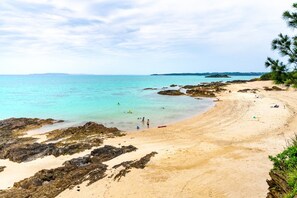 A beach with clear turquoise water, rocky areas, and a sandy shore. - LiB PLUS Villa NAGO (Nago)