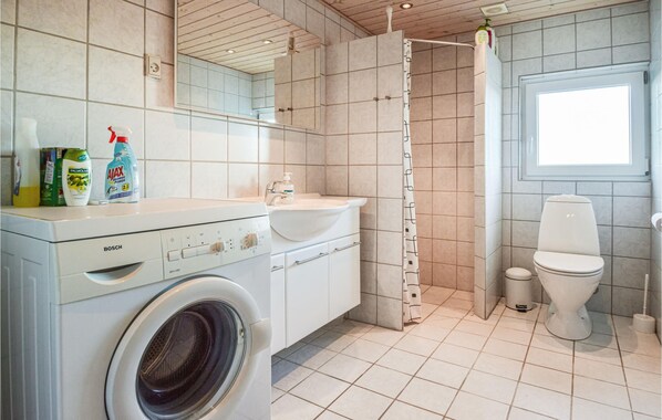 A modern bathroom with a Bosch washing machine, a sink, a toilet, and a shower area. - Cozy home in Hemmet with house sea view (Hemmet)