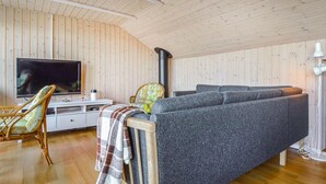 A cozy living room with a sofa, a television, a fireplace, and a wooden ceiling. - Cozy home in Hemmet with house sea view (Hemmet)