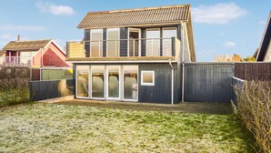 A two-story house with a balcony, large windows, and a fenced backyard. - Cozy home in Hemmet with house sea view (Hemmet)