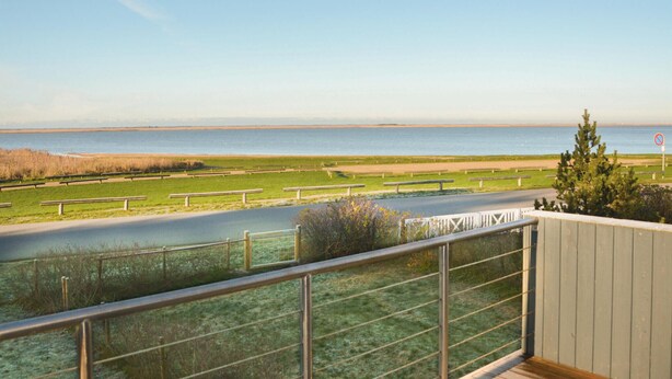 A balcony with a view of a beach, a road, and a no parking sign. - Cozy home in Hemmet with house sea view (Hemmet)