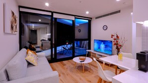 Ein modernes Wohnzimmer mit einem grauen Sofa, einem weißen Couchtisch und einem Fernseher auf einem Schrank.