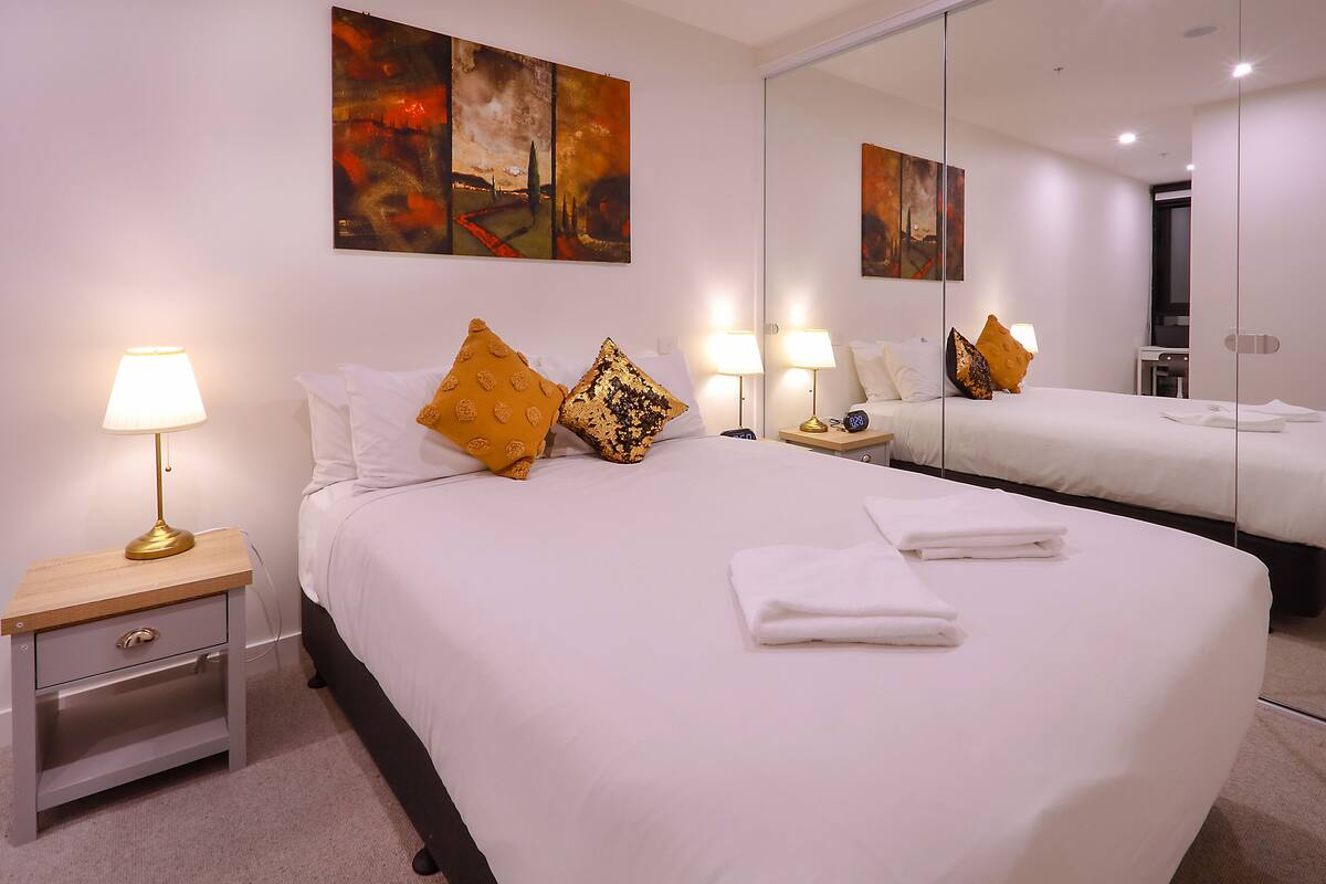 A hotel room with a large bed, two bedside tables with lamps, a mirror, and artwork on the wall.