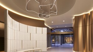 Eine moderne Lobby mit einer gebogenen Bank, einem runden Lichtarmaturen und Blick ins Gebäudeinnere.