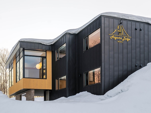 Oguma Lodge features a modern aesthetic with large glass windows and wooden paneling.