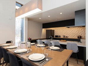 Enjoy meals in this dining area with a long table and comfortable seating, accompanied by a fully equipped kitchen.