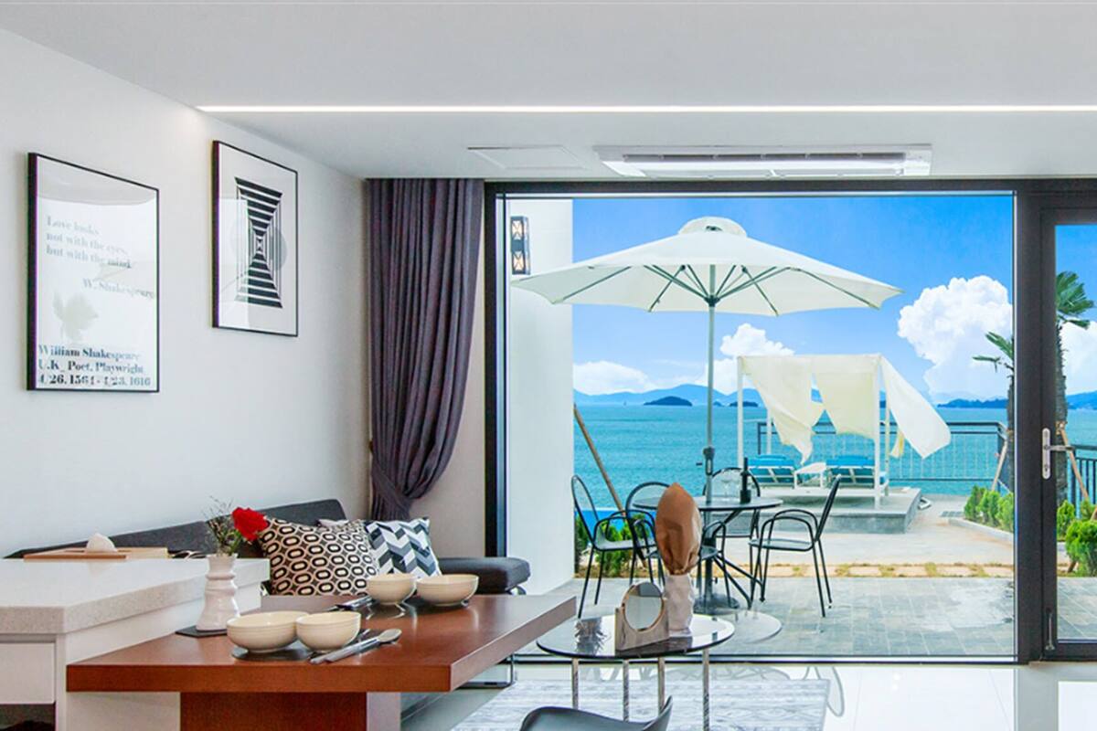 A modern hotel room with a balcony, a dining area, and a TV.