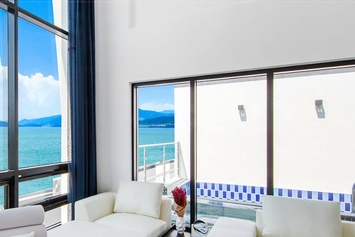 A spacious room with large windows offering a view of the sea and distant islands.