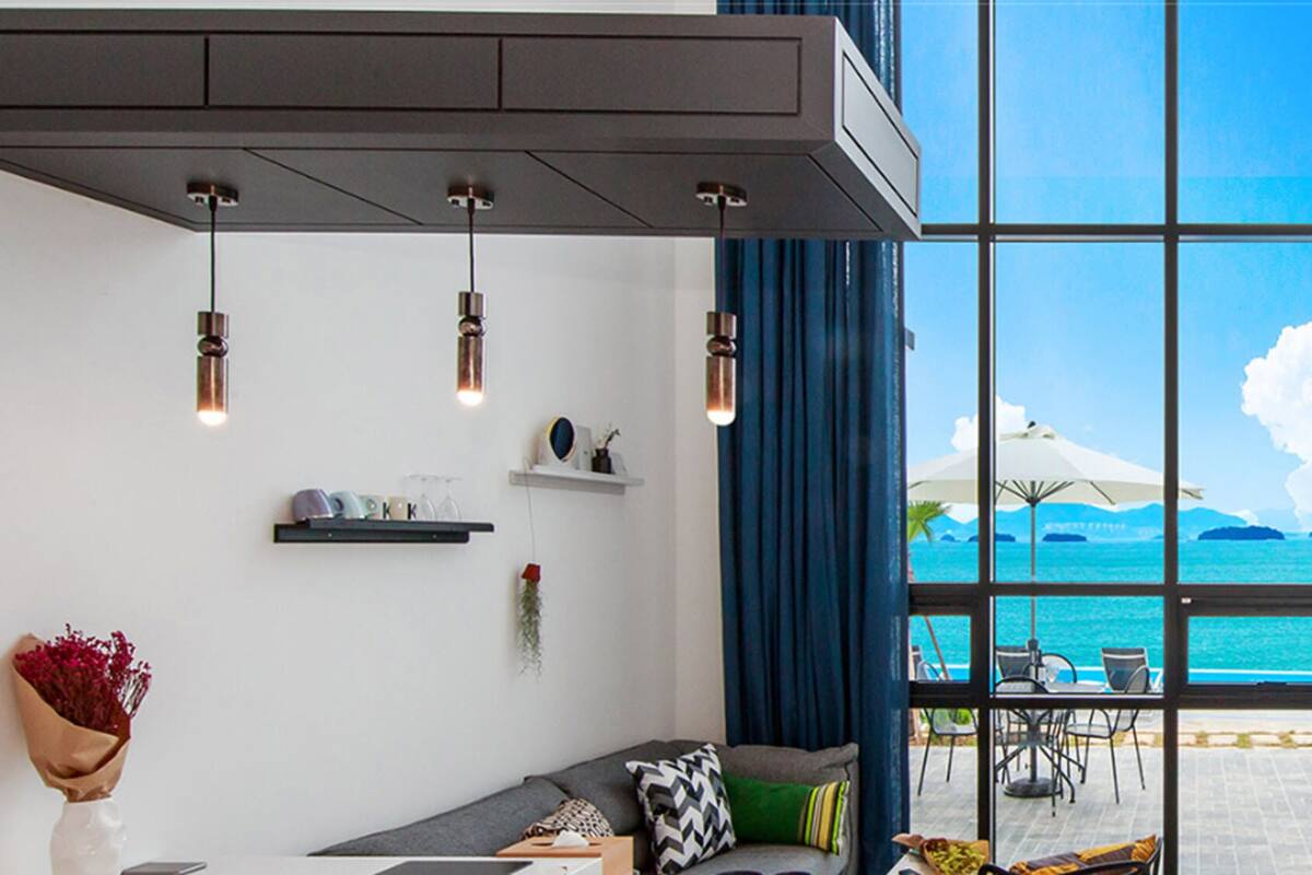 A modern interior with a large window offering a view of the sea and mountains.
