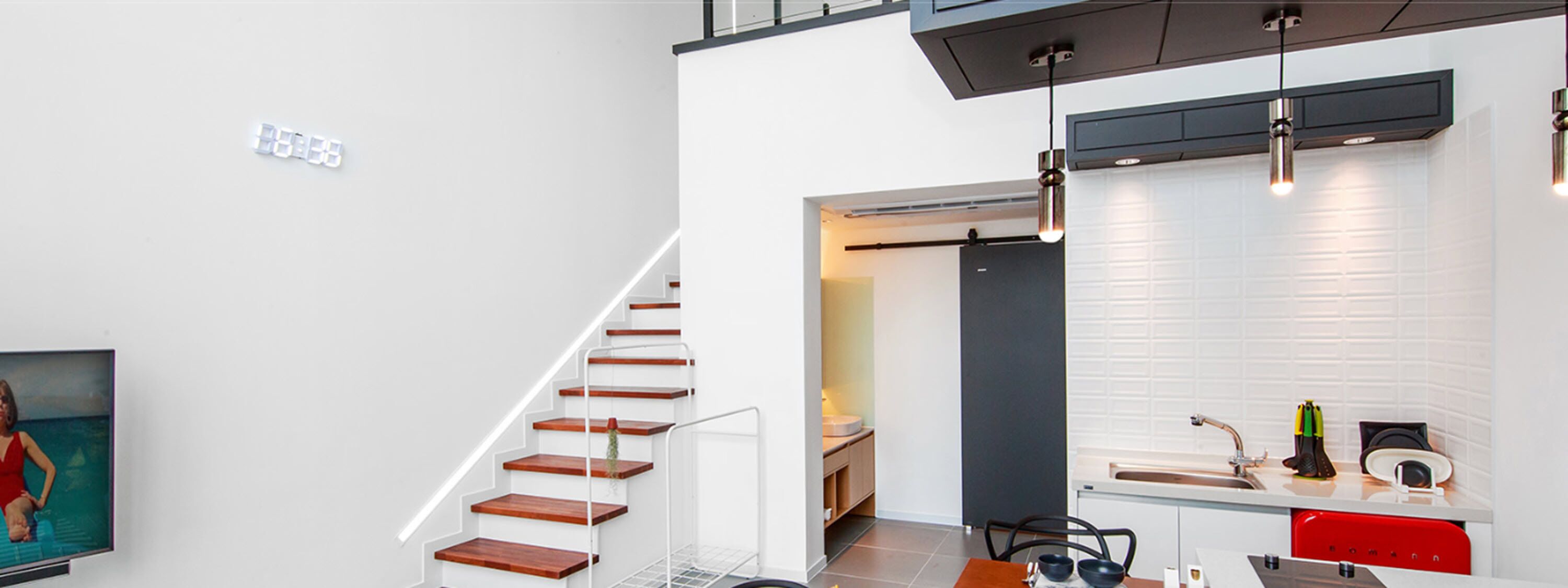 A modern interior with a staircase, a kitchen area, and a dining space.
