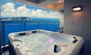 Un jacuzzi con una vista panorámica al océano, una pequeña mesa con una bebida y una silla.