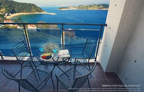 Un balcón con mesa y sillas, con vistas a la costa, un puente y una playa.
