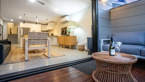 A modern interior with a dining area, a sofa, a wicker table, and a kitchen in the background.