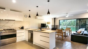 A modern kitchen with white cabinetry, a built-in stove, and pendant lighting.