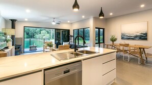 A modern kitchen with a large island, stainless steel appliances, and a dining area with a wooden table and chairs.