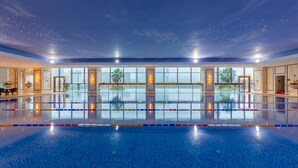 A large indoor swimming pool with clear water, surrounded by walls with large windows. - Oriental Ventura (Lishui)